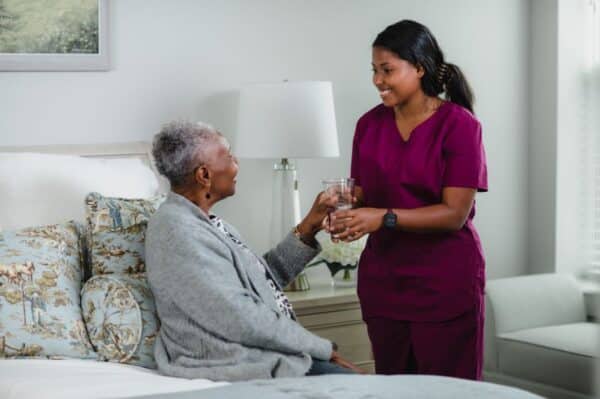 Nurse with Senior Woman Sitting on Bed